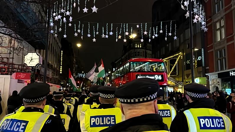 Met officers look on as pro-Palestine protesters march down Oxford Street in London on Tuesday. Photograph: Rosie Shead/PA