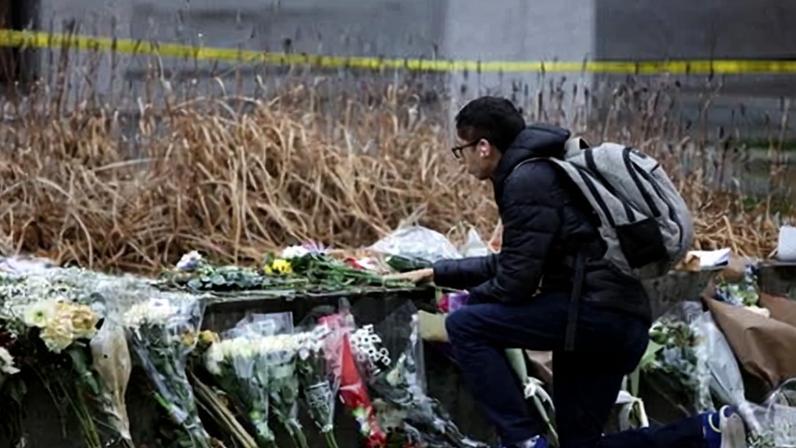 A student lays flowers at a memorial for the victims of the Brown University.