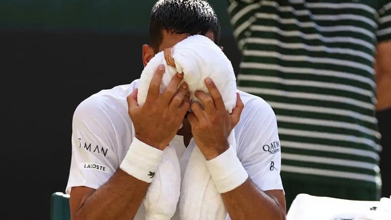 Novak Djokovic tenta aliviar o calor na partida contra o líder do ranking, Jannik Sinner (Foto: HENRY NICHOLLS / AFP)