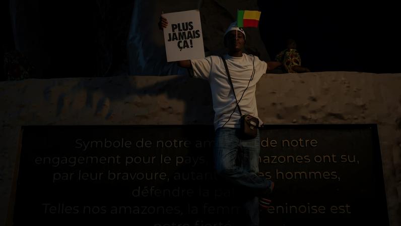 A young man holds a placard during a rally in support of Beninese President Patrice Talon and the country’s democracy at Amazon Square in Cotonou, Benin, on Dec. 13, following a coup attempt earlier that week.