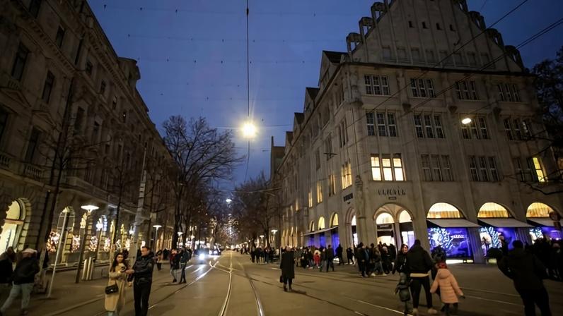 Pessoas caminhando sob iluminação natalina em Rua comercial de Zurique, na Suíça