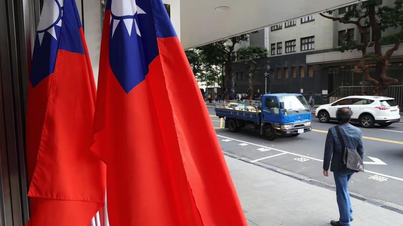 A man walks past Taiwan flags on a street in Taipei