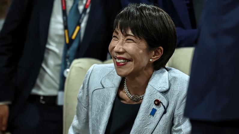 Takaichi smiles wide at something off camera. She wears a silver suit jacket.