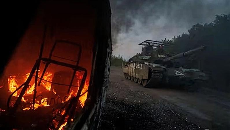 Un carro ucranio con una protección antidrones pasa junto a un vehículo calcinado en Sumi en agosto de 2024