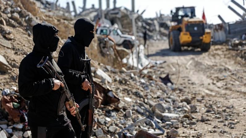 Hamas members stand guard as workers search for the last two bodies of hostages in the northern Gaza Strip on Dec. 1.
