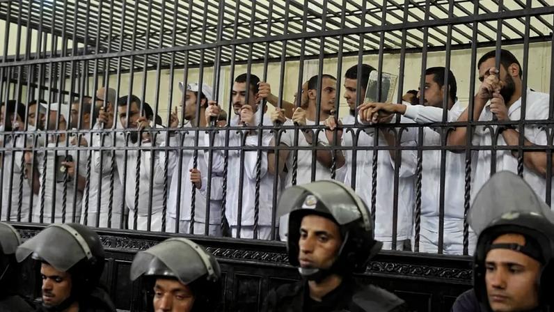 Egyptians stand behind the defendants’ cage during their trial after the army overthrew Egypt’s ousted Islamist president, Mohamed Morsi.