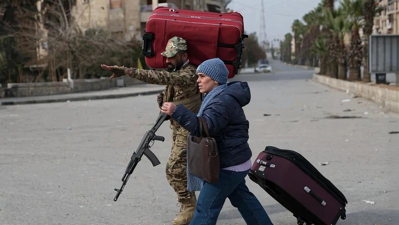 Um soldado sírio ajuda um morador a fugir dos bairros predominantemente curdos de Sheikh Maqsud e Ashrafiyeh, na cidade de Aleppo, norte da Síria, em 8 de janeiro de 2026, em meio a intensos confrontos entre as forças governamentais e as Forças Democráticas Sírias (FDS), lideradas pelos curdos.