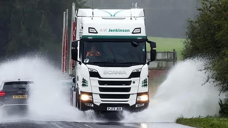 Getty Images A lorry and car drive through flood water on a country road