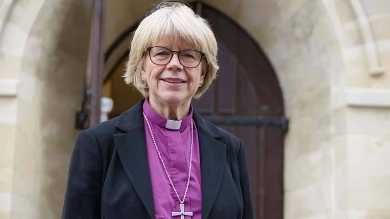 Sarah Mullally stands outside a church's arched doorway