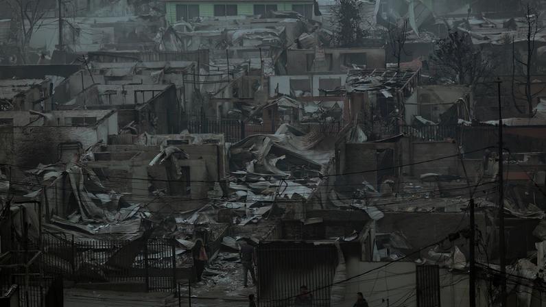 People stand among charred and heavily damaged properties in Concepcion, Chile, in the aftermath of a forest fire in the Biobio region, where, according to local media, multiple wildfires prompted emergency evacuations, January 18, 2026. REUTERS/Juan Gonzalez