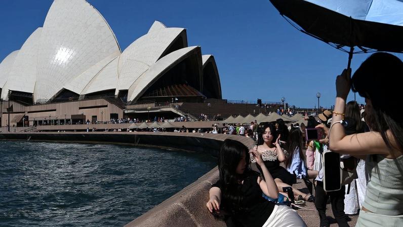 People take pictures near the Sydney Opera House, in Circular Quay, during hot weather in Sydney, Australia, January 27, 2026. REUTERS/Flavio Brancaleone