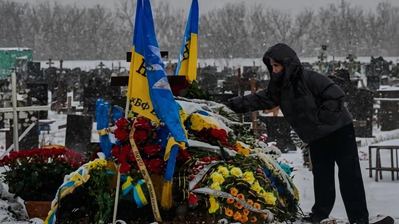 A Ukrainian visits a grave on the Alley of Heroes at the military cemetery in Kharkiv.
