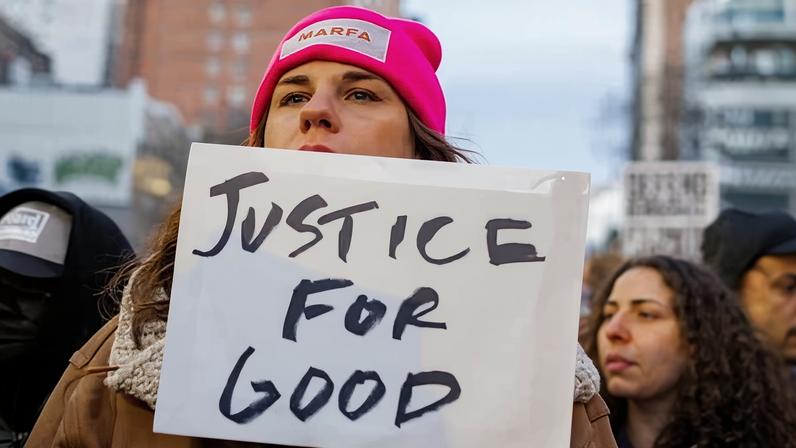 A person carries a sign referencing the killing of Renee Good during an anti-ICE protest in New York City on 23 January.