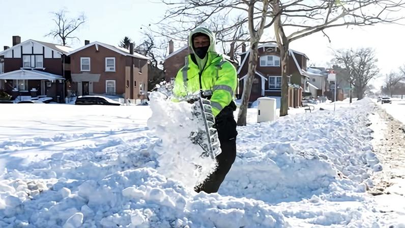 A city worker shovels snow from a sidewalk in a residential neighborhood in the aftermath of a winter storm in the St Louis area, Missouri, on Monday.