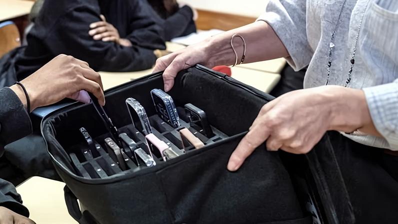 A teacher collects a student's mobile phone ahead of class in the northern suburbs of Paris. French president Emmanuel Macron has championed a new bill which would see social media banned for under-15s, similar to Australia’s recent law.