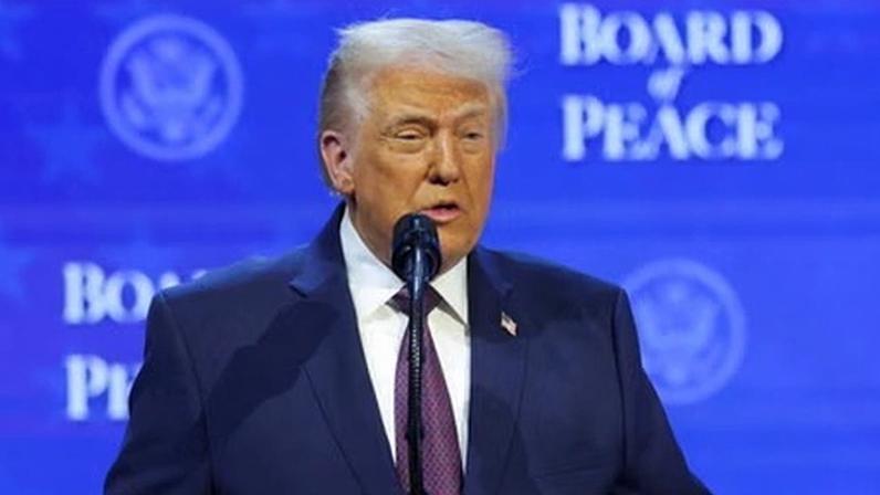 Donald Trump holds up a folder containing a signed charter of the ‘board of peace’