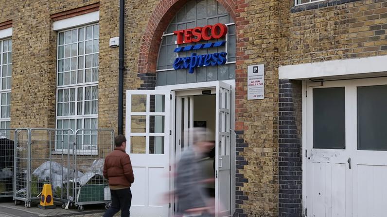 Shoppers walk past a branch of Tesco in London