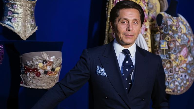 Valentino poses in front of some of his designs