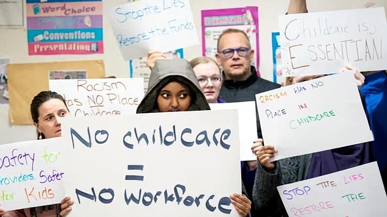 Parents, teachers, childcare workers and community members hold up handmade signs during a press conference at Nokomis Daycare Center in Minneapolis, Minn. on 31 December 2025.
