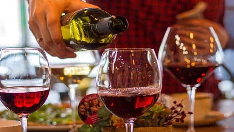 Person pours the red wine into three glasses – slightly out of focus