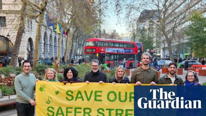 Campaigners hold up a ‘save our safer streets’ sign near a busy London street.