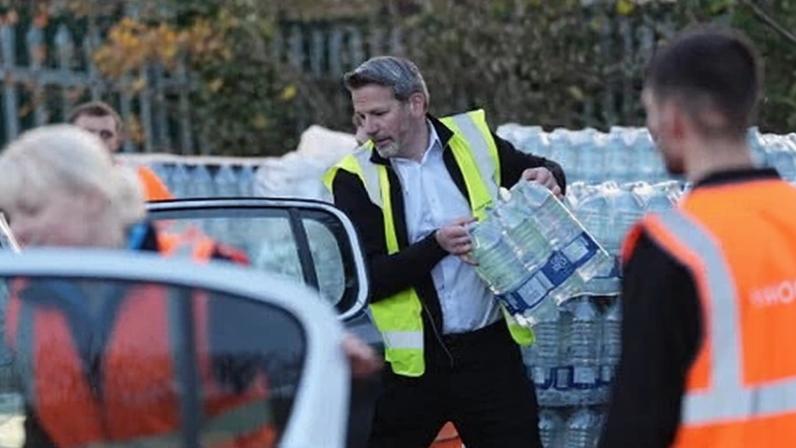 People in hi vis load bottled water into cars