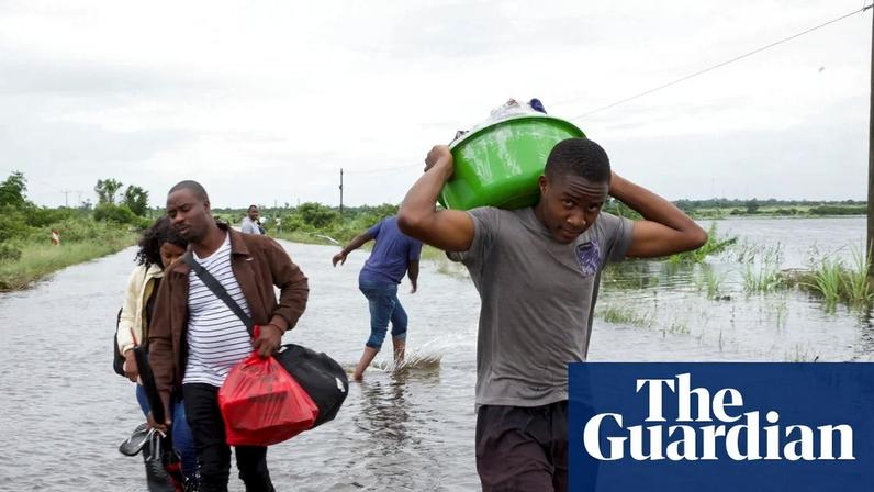 People walk through ankle-deep water carrying belongings