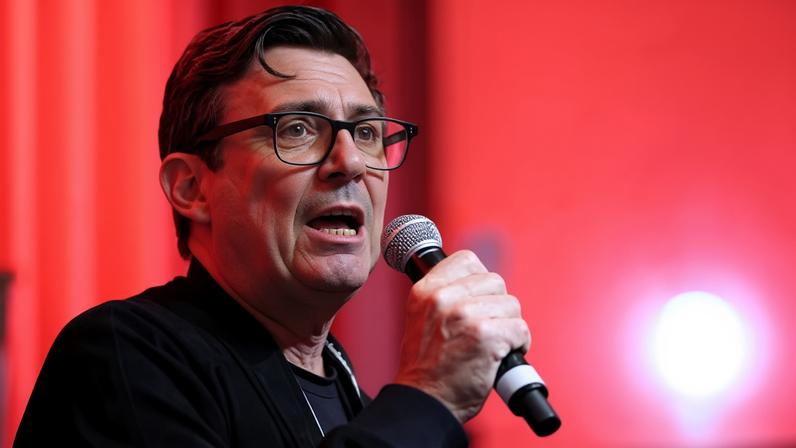 Andy Burnham speaking into a microphone