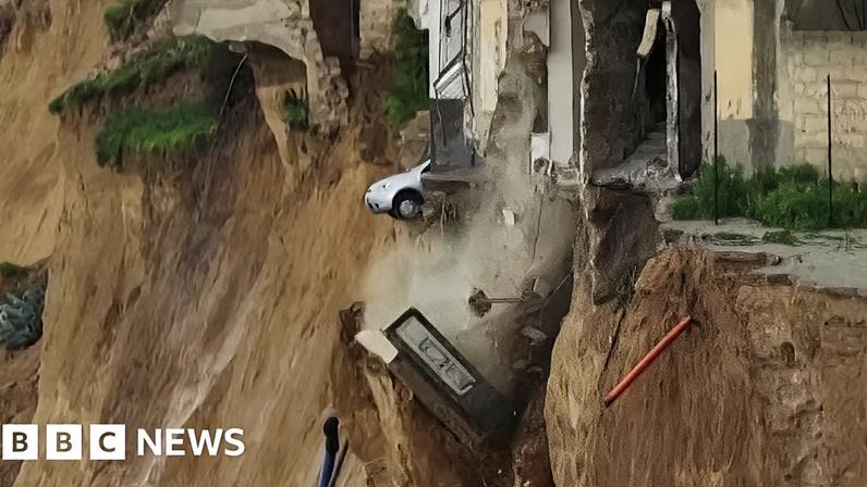 A car teetering on the edge of a drop after a landslide