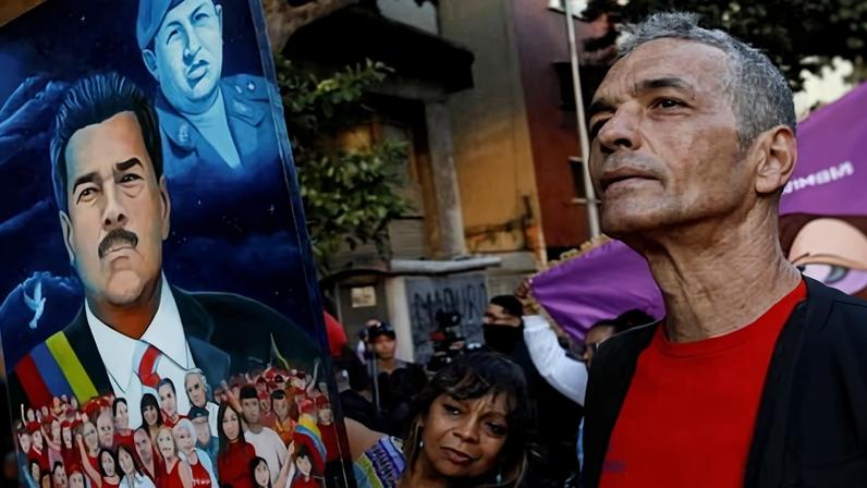 A supporter of Maduro holds a painting of him in Caracas.