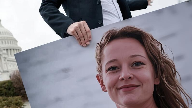 An aide collects a photo of Renee Good after a press conference at the US Capitol in Washington on 14 January.