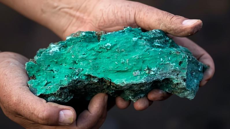 Closeup of hands holding green-coloured rock