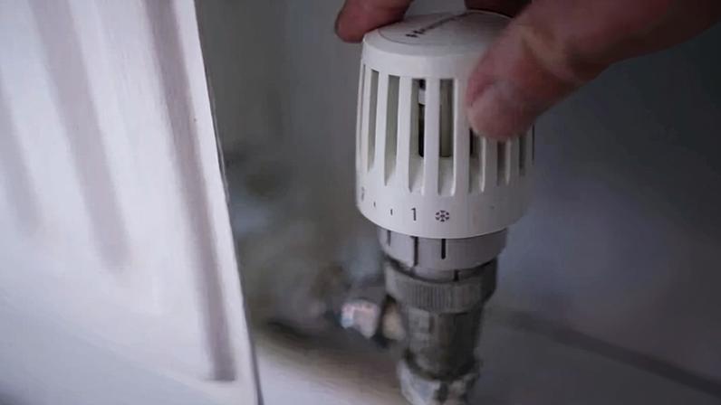 Someone turning the dial on a domestic radiator thermostat
