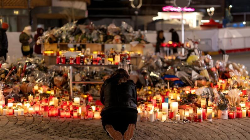 A woman lights a candle at a makeshift memorial outside the "Le Constellation" bar, after a deadly fire and explosion during a New Year's Eve party, in the upscale ski resort of Crans-Montana in southwestern Switzerland, January 5, 2026.
