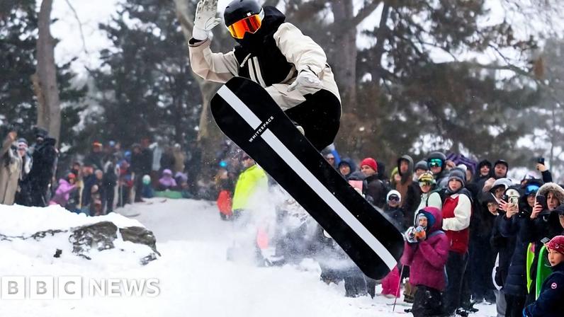 Shaun White does a snowboard flip in front of onlookers.