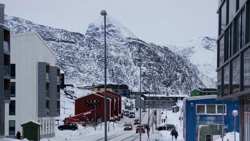 People walk along a snow-covered street in Nuuk city, Greenland