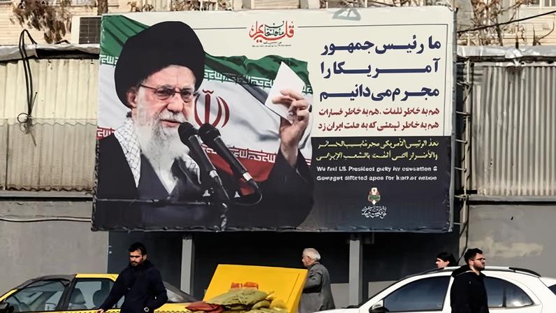 Iranians walk past a billboard in Tehran showing the supreme leader, Ali Khamenei, alongside anti-US rhetoric on 27 January.