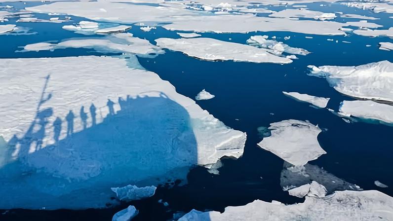 the shadow of human figures on a ship cast over some arctic sea ice