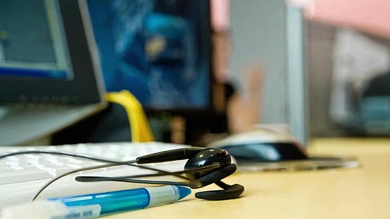 A call centre photo with a headset on a desk near a computer.