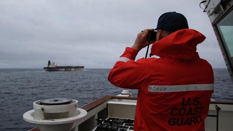 A U.S. Coast Guard official looks through binoculars at the ship Marinera (Ex-Bella 1) in this handout image released January 7, 2026. US EUROPEAN COMMAND via X/Handout via REUTERS