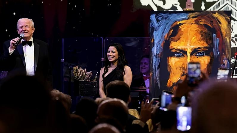 Donald Trump stands next to Vanessa Horabuena as he auctions her painting at Mar-a-Lago.