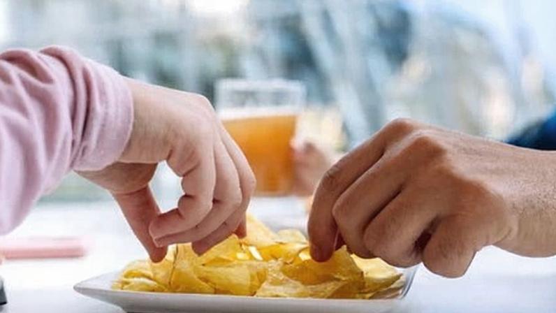 Close-up of the hands of people eating crisps.