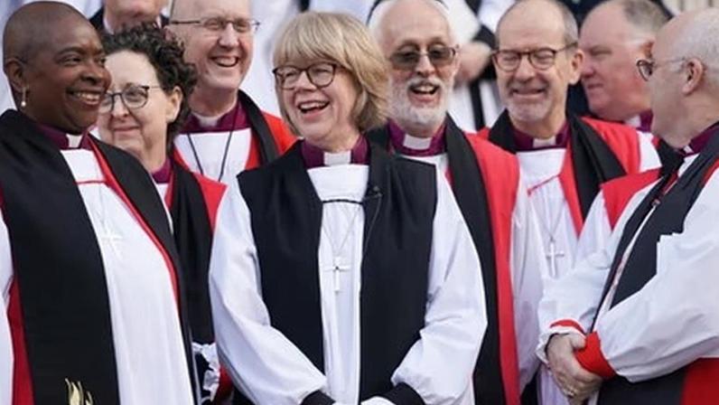 Sarah Mullally holds arms in the air in jubilant gesture in robes