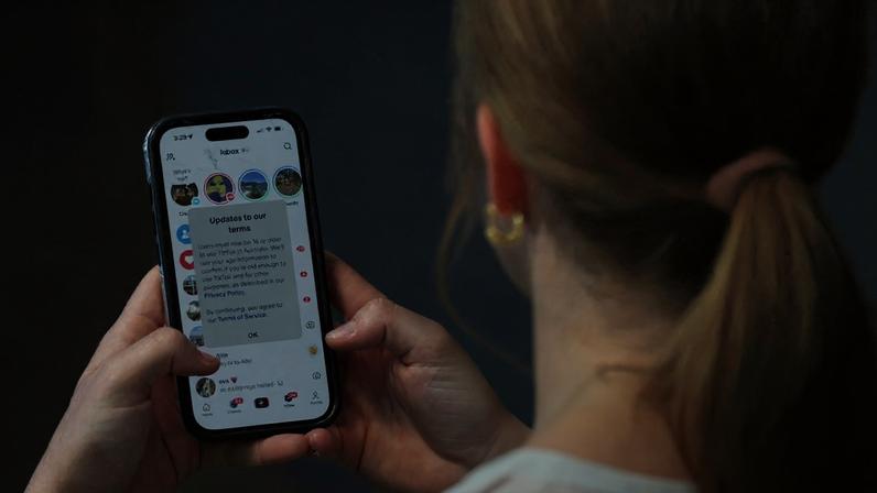 A teenager holding a mobile phone displaying a message from TikTok in Sydney, where a law banning social media for users under 16 in Australia has taken effect.