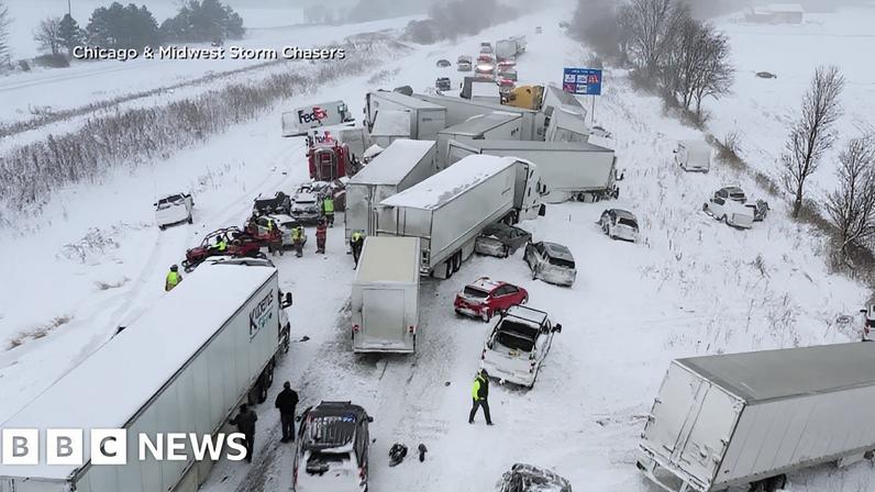 A group of trucks and cars in a collision on a snowy motorway.