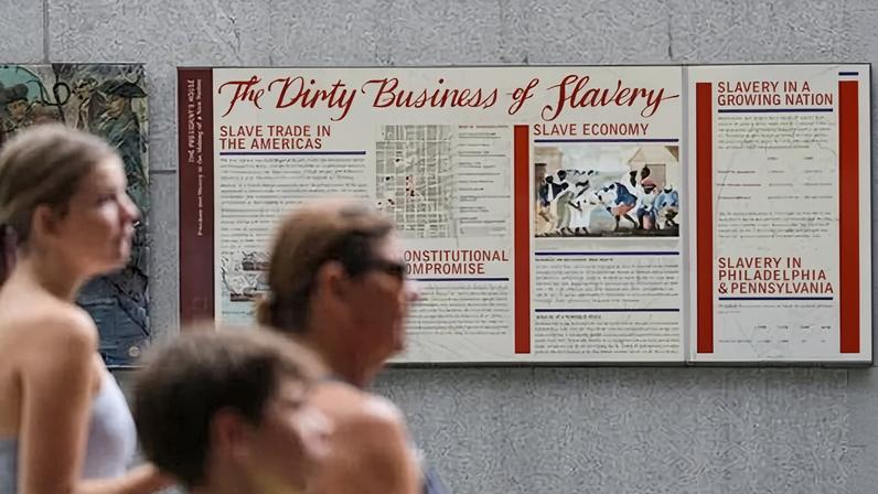 People walk past an informational panel at President's House Site on 19 August 2025, in Philadelphia.
