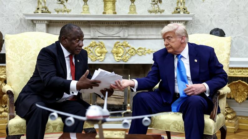 U.S. President Donald Trump hands over to South African President Cyril Ramaphosa copies of articles that he said showed white South Africans who had been killed, in the Oval Office of the White House in Washington, D.C., U.S., May 21, 2025. REUTERS/Kevin Lamarque