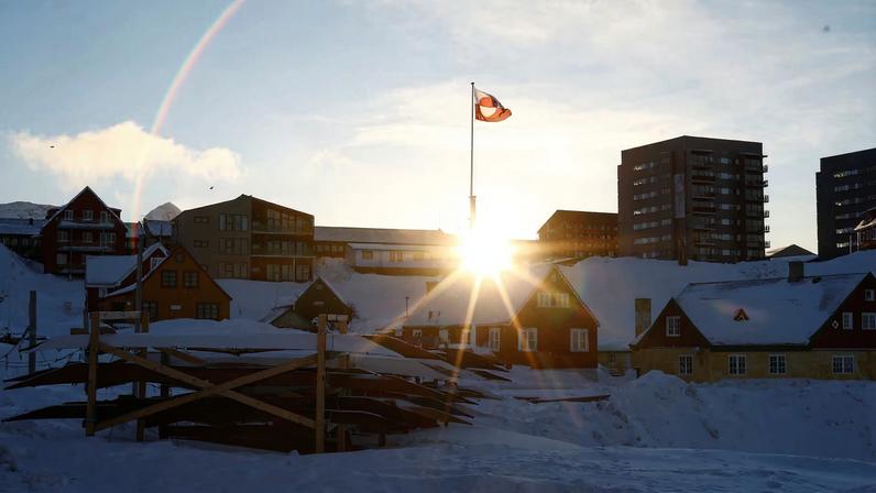 The sun rises behind Greenland's flag in Nuuk's old harbor, Greenland, February 5, 2025. REUTERS/Sarah Meyssonnier