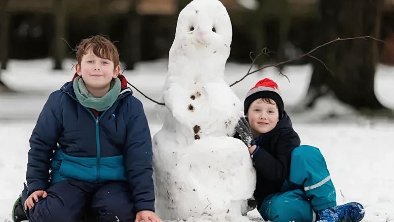 Brothers Eoin and Rory, from Antrim, with their snowman in Antrim Castle Gardens