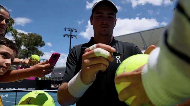 João Fonseca autografa bola após treino no Australian Open (Foto; DAVID GRAY / AFP)